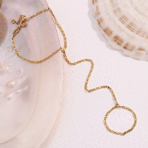 Detailed macro view of 18K gold-plated pig nose link hand harness with ring set on seashells