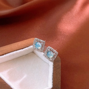Boucles d'oreilles carrées en argent avec opale bleue et zircons sur présentoir blanc