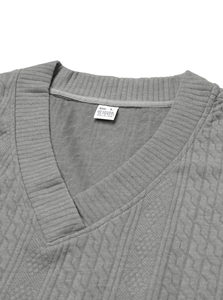 Detail view of the V-neckline and fabric texture of a gray knitted sweater with wash label