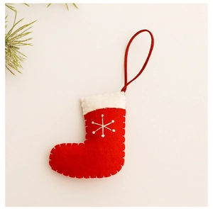 Detail of red knit Christmas stocking ornament with white embroidered snowflake pattern