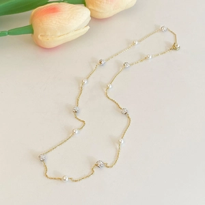 Vue détaillée d'un collier en chaîne dorée avec perles brillantes et boules de zircon