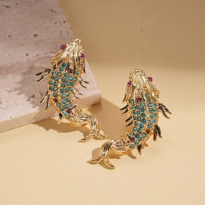 Detail of luxury gold carp earrings with vibrant turquoise and purple rhinestones