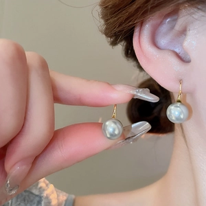 Close-up of 18K gold pearl earrings showing elegant grey pearls on the earlobes