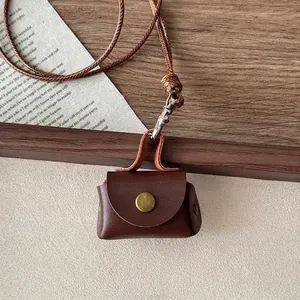 Close-up of retro brown leather pendant case with woven lanyard and metal clasp detail
