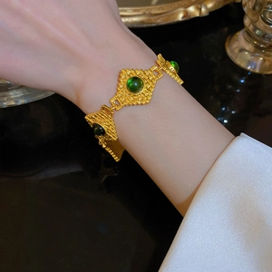 Detailansicht eines antiken goldenen Armbands mit grünen Edelsteinen im eleganten Palaststil.