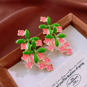 Detail of vintage floral earrings with pink petals and green leaves on velvet tray