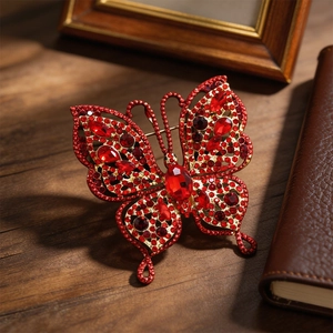 Broche papillon vintage avec cristaux rouges et finition dorée sur bois sombre