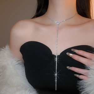 Close-up of a silver Y-shaped tassel necklace with sparkling rhinestones on a model