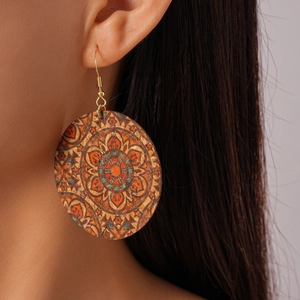 Close-up of bohemian leather earrings with geometric mandala print on female model