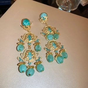 Vue détaillée des boucles d'oreilles vintage dorées ajourées avec perles en résine et strass