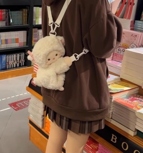 Detail of adjustable white strap on cute cream plush animal backpack in a library setting