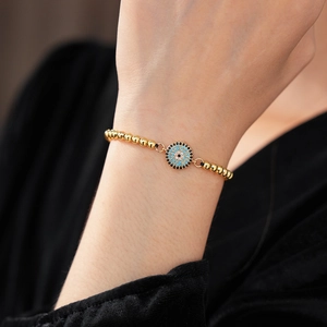 Détail du bracelet ajustable en zircon œil bleu avec finition dorée sur le poignet