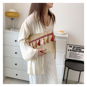 Straw envelope clutch bag with colorful tassels and linen texture shown in lifestyle setting