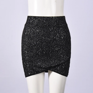 Detail of black mini skirt featuring white polka dot print and stylish crossover hem design