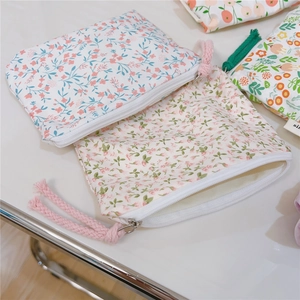 Close-up of floral cotton coin purses with zipper closures and rustic rope pulls