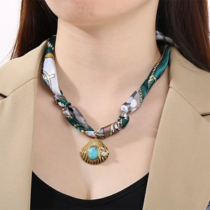 Détail du collier écharpe en soie avec pendentif coquillage doré et pierre turquoise