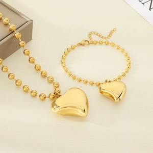 Detail of golden stainless steel beaded jewelry set with 3D heart-shaped pendants