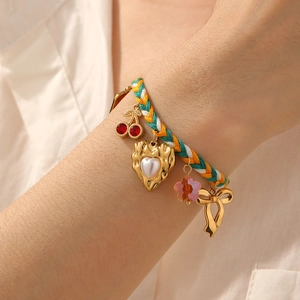 Colorful woven cord bracelet with cherry heart charms and pearl accents on wrist