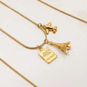 Detailed close-up of 18K gold stainless steel charms featuring a plane and Eiffel Tower