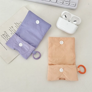Dettaglio delle custodie per AirPods in tessuto trapuntato color viola e albicocca.