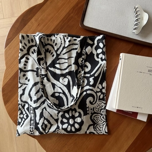 Gros plan du sac en lin bohème avec motif d'art abstrait noir et blanc sur une table en bois