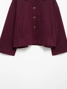 Detail of burgundy wool coat showing amber buttons and symmetrical vertical pockets