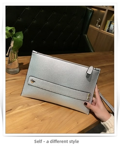 Detail van zilveren envelop-clutch met litchi-patroon textuur en metalen klinknagelaccenten