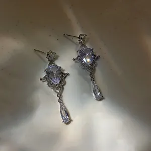 Macro detail of drop-shaped zircon earrings with baroque hollow silver metalwork