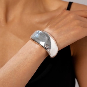 Close-up of a wide polished silver cuff bracelet with a reflective mirror finish