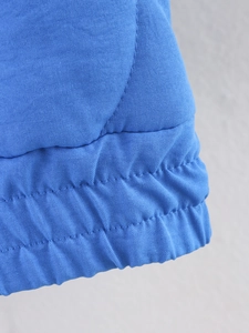 Detail shot of blue ethnic quilted coat showing the elastic hem and woven fabric texture