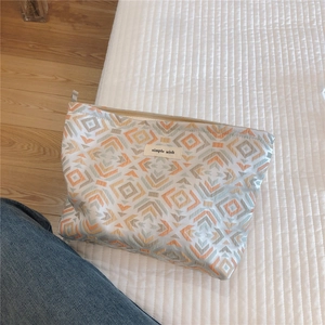 Macro detail of geometric patterned woven cosmetic bag with simple wish label and zipper