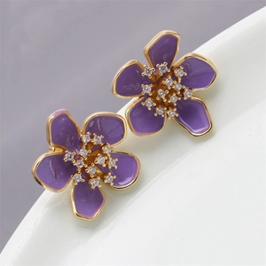 Macro view of purple enamel flower earrings with gold edges and zircon center