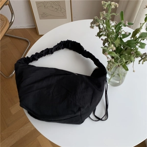 Dettaglio macro della borsa hobo in nylon nero con tracolla arricciata a effetto nuvola