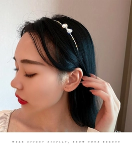 Detail view of a metallic bow headband with sparkling rhinestones worn by a model