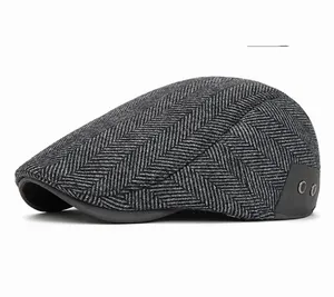 Detail of dark gray herringbone newsboy hat with thick wool texture and metal eyelets