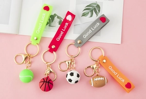 Detail of sports-themed keychains with soccer, basketball, tennis, and rugby soft charms