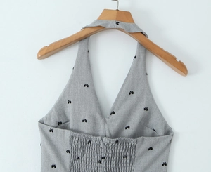 Close-up of grey striped halter top with black butterfly embroidery on wooden hanger