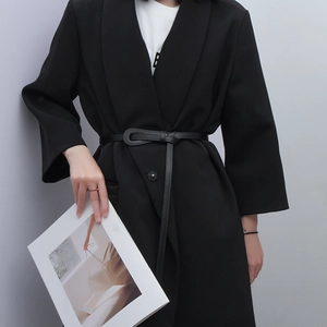 Detail of a slim black leather waist belt tied on a blazer for a minimalist fashion look