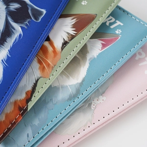 Close-up of stacked faux leather passport covers with cute pet prints and stitching