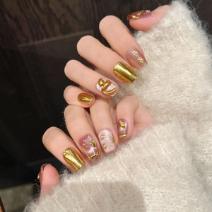 Short square press-on nails with 3D gold snake motifs and pearl accents on hand