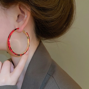 Detail of large hoop earring featuring red leopard print and golden metallic inner lining