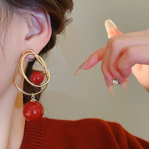 Gros plan détaillé des boucles d'oreilles doubles billes rouges et anneaux dorés