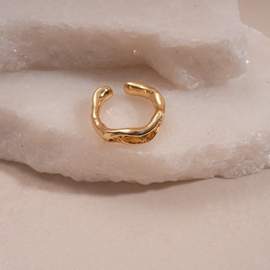 Detail of gold liquid metal lava ring placed on white natural stones with elegant lighting