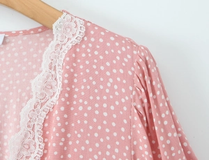 Close-up of pink polka dot dress with delicate white lace collar on a wooden hanger