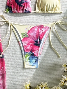 Detailed flat lay of floral bikini set with halter top and side-tie bottoms on beige fabric