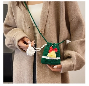 Detail of Christmas handmade crochet bag with green knit texture and golden bell ornament