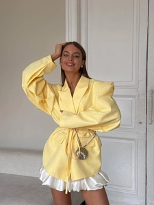 Detail des gelben Oversize-Blazers mit Taillengürtel und goldener Muscheltasche