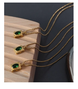 Detail of 18K gold plated beaded chain with oval green zircon pendant on wooden stand
