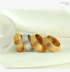 Macro shot of gold and silver layered geometric rings on white silk background