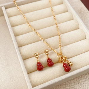 Detail of red gourd necklace and earrings set in a beige velvet jewelry gift box